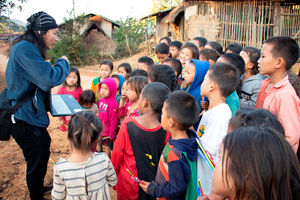 Givers of Dreams Founder Her Vang talks to a group of kids in a remote village.